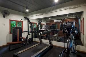 Fitnessraum im Khaolak Paradise Resort mit Laufband, Hanteln und einem großen Spiegel.