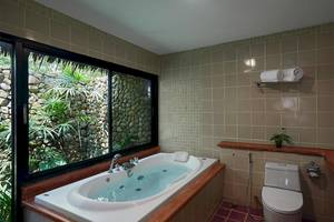 Ein Badezimmer mit einer Badewanne und einem Fenster, das einen Garten zeigt.