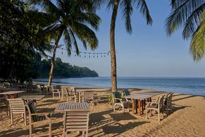 Sitzplätze am Strand des Khaolak Paradise Resorts mit Blick auf das Meer und Palmen.