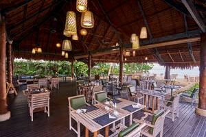 Das Esszimmer des Khaolak Paradise Resorts mit Holztischen und Stühlen, hängenden Laternen und Blick auf den Strand.