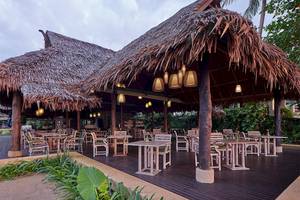 Außenbereich des Khaolak Paradise Resorts mit Tisch und Stühlen unter einem Strohdach.