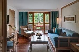 Wohnzimmer des Santiburi Koh Samui Hotels mit Blick auf eine Terrasse und Garten.