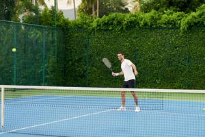 Tennisspieler auf blauem Platz im Hotel Santiburi Koh Samui