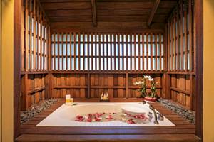 Japanischer Badepool im Buri Rasa Village Samui mit Rosenblättern und einem blauen Getränk.