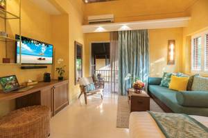 Wohnzimmer des Buri Rasa Village Samui Hotels mit Fernseher, Laptop, Couch und Bett.