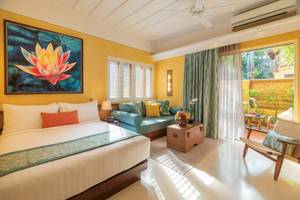 Innenansicht eines Zimmers im Buri Rasa Village Samui Hotel mit Bett, Couch, Kunstwerk und Terrassentür.