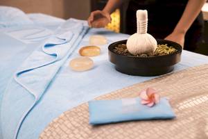 Massagetisch im Saadiyat Rotana Resort mit drei Steinen, einem Beutel und einer Blume.