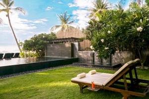 Ein Gartenbereich des Buri Rasa Village Samui Hotels mit einem Pool, Liegen und Pflanzen.