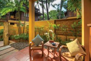 Terrasse des Buri Rasa Village Samui Hotels mit zwei Holzstühlen, einem kleinen Tisch und Kissen.