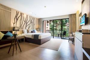 Innenansicht eines modernen Hotelzimmers mit Bett, Couch, Tisch, Fernseher und Balkon.
