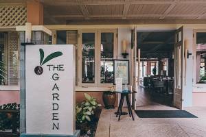 Eingang zu The Garden im Khao Lak Merlin Resort mit Beschilderung und Tischen draußen.