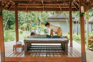 Massage im Pavillon im Khao Lak Merlin Resort mit einer Frau, die einen Mann massiert.