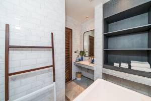 Badezimmer im Peace Resort mit Badewanne, Dusche, Toilettenpapierhalter und Regal mit Handtüchern.