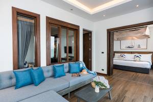 Wohnzimmer der Ferienwohnung in Friedrichshafen mit Sofa, Tisch und offenem Schlafzimmer.