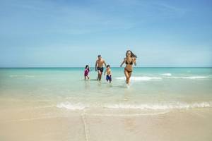 Eine Familie läuft am Strand im Saadiyat Rotana Resort & Villas.