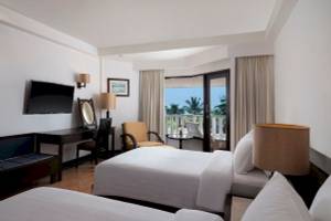 Zimmer im Aonang Villa Resort mit zwei Betten, Balkon und Aussicht auf Palmen und Meer.
