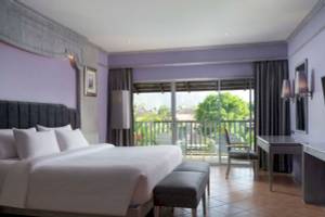 Schlafzimmer im Aonang Villa Resort mit großem Bett, Balkon und Ausblick auf Bäume.