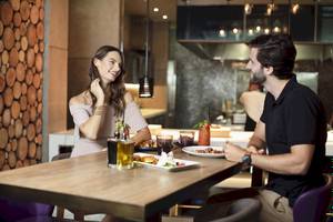 Ein Paar sitzt im Saadiyat Rotana Resort & Villas Restaurant und lächelt