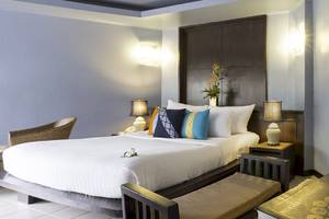 Doppelbett-Zimmer im Peace Laguna Resort & Spa mit weißen Bettlaken, Kissen und Nachttischen mit Lampen.