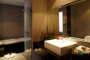 Badezimmer mit Badewanne, Spiegel, Waschbecken und Blumendekoration