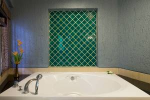 Badezimmer mit großer Badewanne und Blumenvase im Peace Laguna Resort & Spa
