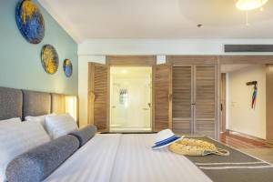 Ein modernes Hotelzimmer mit einem großen Bett, mehreren Kissen und Accessoires wie einem Hut und einer Tasche.