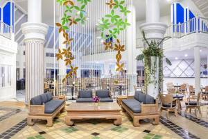 Hotellobbybereich mit Sofas, Tischen, dekorativen Wandschirmen und gefliestem Boden.