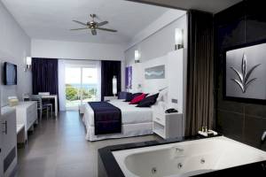 Innenansicht einer Suite im Riu Palace Costa Rica mit großem Bett, Badewanne und Meerblick.