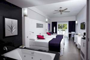 Innenansicht der Suite im Riu Palace Costa Rica mit zwei Betten, Badewanne und modernen Möbeln.