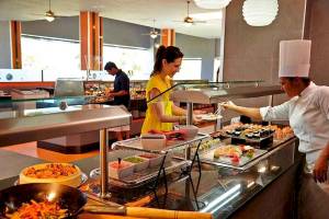 Im Restaurant des Riu Palace Costa Rica bereitet ein Koch Sushi zu, während eine Frau bedient wird.