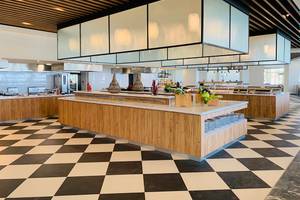 Innenbereich des Restaurants im Creta Princess Aquapark & Spa Hotel mit Holzmöbeln und schwarz-weißem Boden.