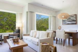Wohnzimmer im El Mangroove, Autograph Collection mit großem Fenster, weiße Möbel und Ausblick auf Bäume