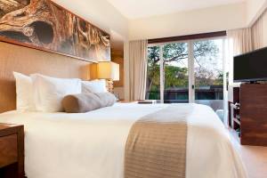 Schlafzimmer im El Mangroove, Autograph Collection Hotel mit großem Bett, Fenstern und Fernseher.