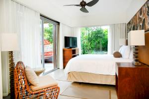 Innenansicht des Hotelzimmers El Mangroove, Autograph Collection mit Bett, Fernseher und Aussicht auf Bäume.