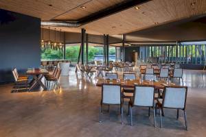 Innenbereich des El Mangroove, Autograph Collection Hotels mit Tisch und Stühlen, hoher Decke und Holzboden.