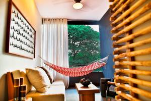 Wohnzimmer eines Hotels mit einem roten und weißen Hängematten über einem Sofa und einem Ausblick auf einen Baum.