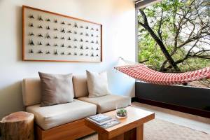 Wohnzimmer mit Sofa, Kissen, Couchtisch, Hängematte und einem Wandbild mit Haifischzähnen.