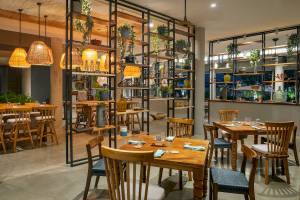 Innenbereich des El Mangroove, Autograph Collection Restaurants mit Holztischen und Stühlen, Pflanzen und Regalen.