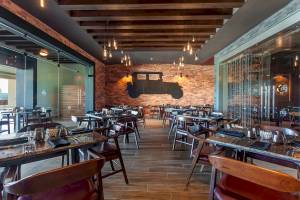 Innenraum des Restaurants im Planet Hollywood Beach Resort mit Tisch und Stühlen, Holzboden und einer Wand mit einem Autodesign.