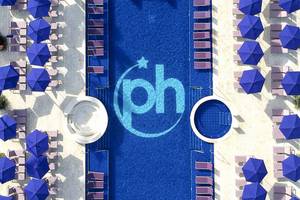Luftaufnahme des Pools mit blauen Sonnenschirmen und Liegen um den Pool herum, Logo PH im Pool.