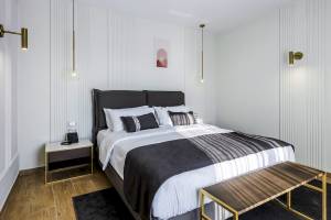 Schlafzimmer im Mövenpick Hotel Lalez Durres mit weißem Bett, goldfarbenen Lampen und modernem Design.