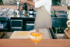 Cocktail Bar im Epidamn White Sensation Hotel mit einem fertigen Getränk und einer Person, die einen Cocktail zubereitet.