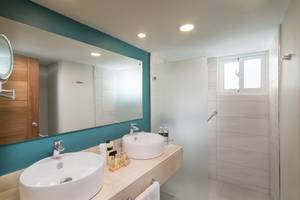 Badezimmer im Emotions By Hodelpa Hotel mit zwei Waschbecken, Spiegel und Duschkabine.