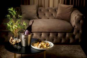 Ein Sofa mit einem Tisch davor, auf dem eine Flasche, Obst und Gläser stehen.