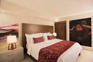 Schlafzimmer im Emotions By Hodelpa Hotel in Puerto Plata mit einem großen Bett, Kunstwerken an der Wand und Nachttischen.