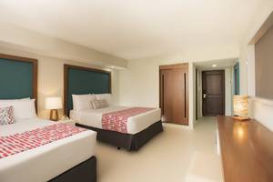 Doppelbett-Zimmer im Emotions By Hodelpa Hotel in Puerto Plata mit zwei Betten, Lampen und Nachttischen.