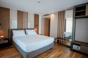 Schlafzimmer im Klajdi Resort & SPA Hotel mit einem großen Bett und weißen Laken, zwei Nachttischen und einem Spiegel.