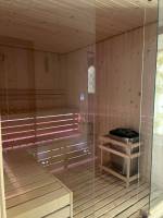 Innenansicht der Sauna im Klajdi Resort mit Holzwänden und Bänken, die mit roten Lichtern beleuchtet sind.