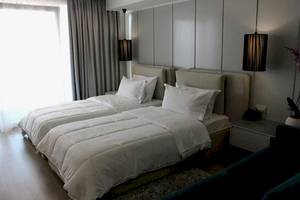 Zwei Betten im Schlafzimmer des Demi Hotels, beide mit weißen Decken und Kissen.