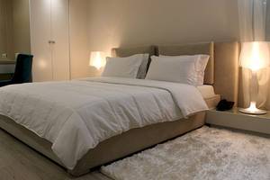 Schlafzimmer im Demi Hotel mit einem großen Bett, weißen Decken und Kissen, und Nachttischen mit Lampen.